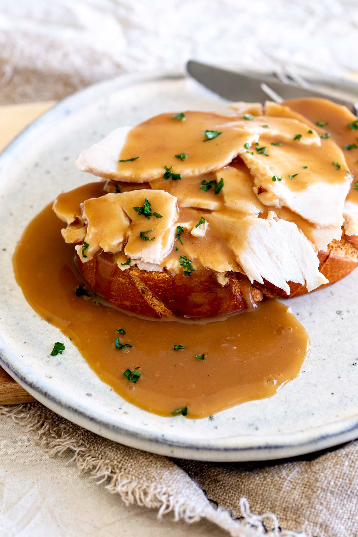 grey plate with a slice of bread, with turkey and gravy on it