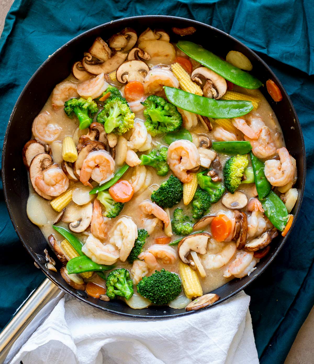 a skillet full of shrimp and vegetables in a white Chinese sauce