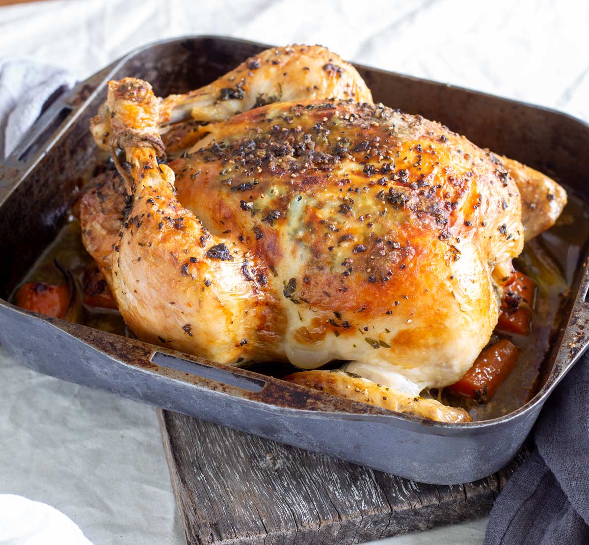 a cooked chicken in a roasting tin with veggies