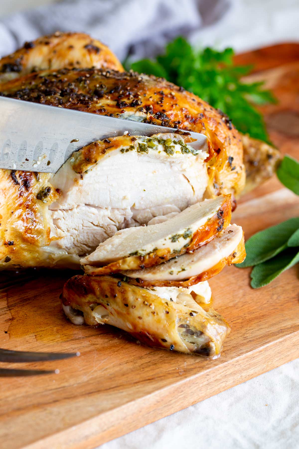 a knife slicing the breast of a roast chicken
