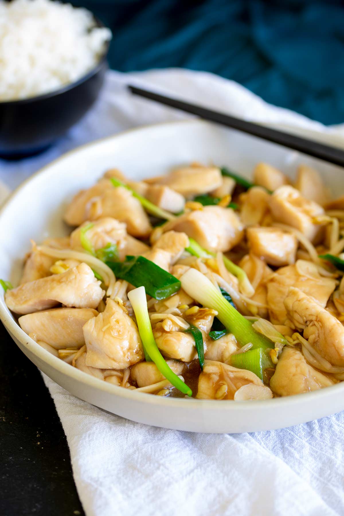 a bowl of Chinese garlic chicken with a bowl of white rice behind