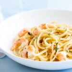 shrimp rosemary pasta in a white bowl of a blue table