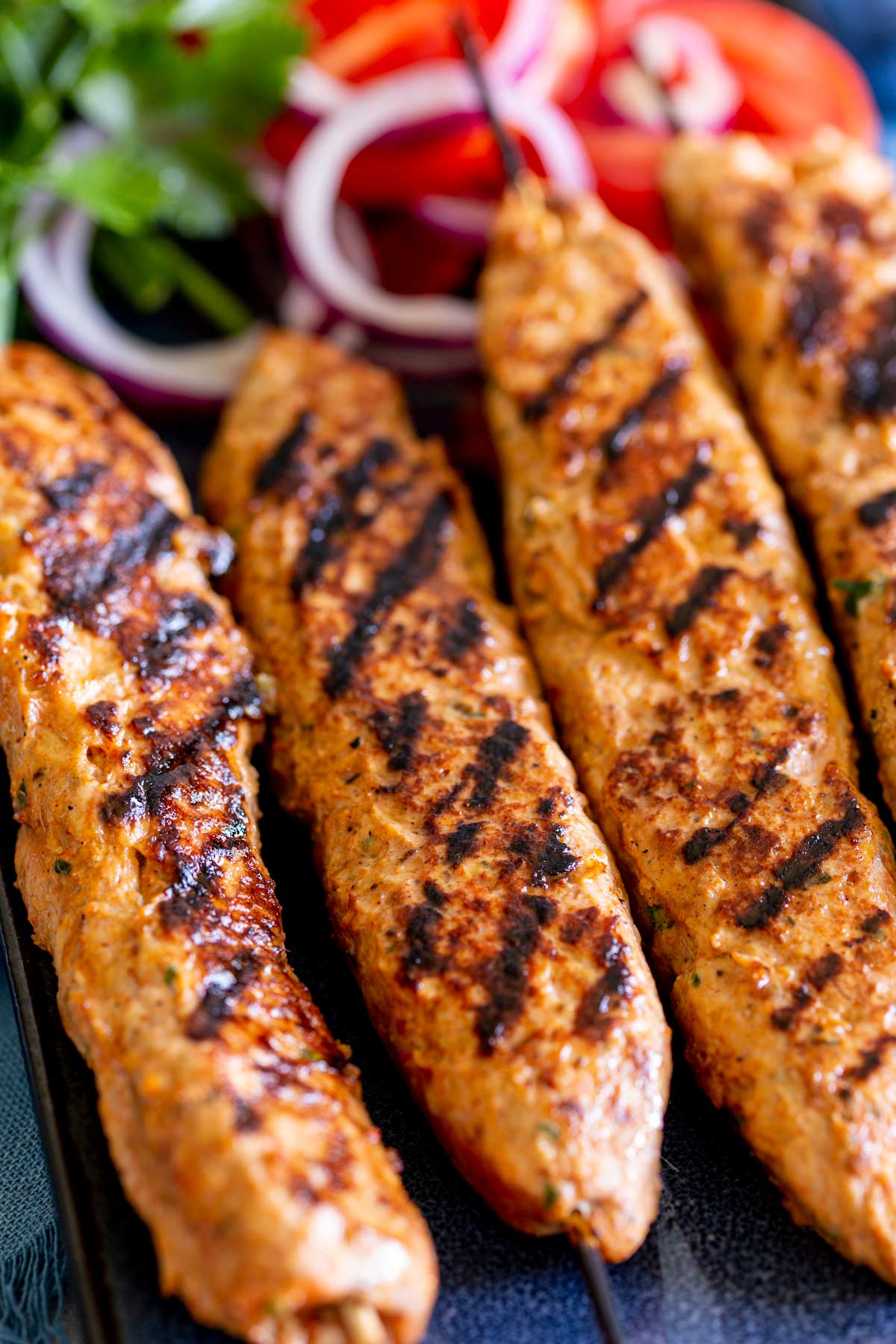 four grilled ground chicken kebabs on a plate