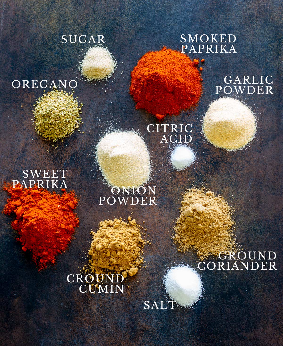 piles of labelled spices on a dark brown table