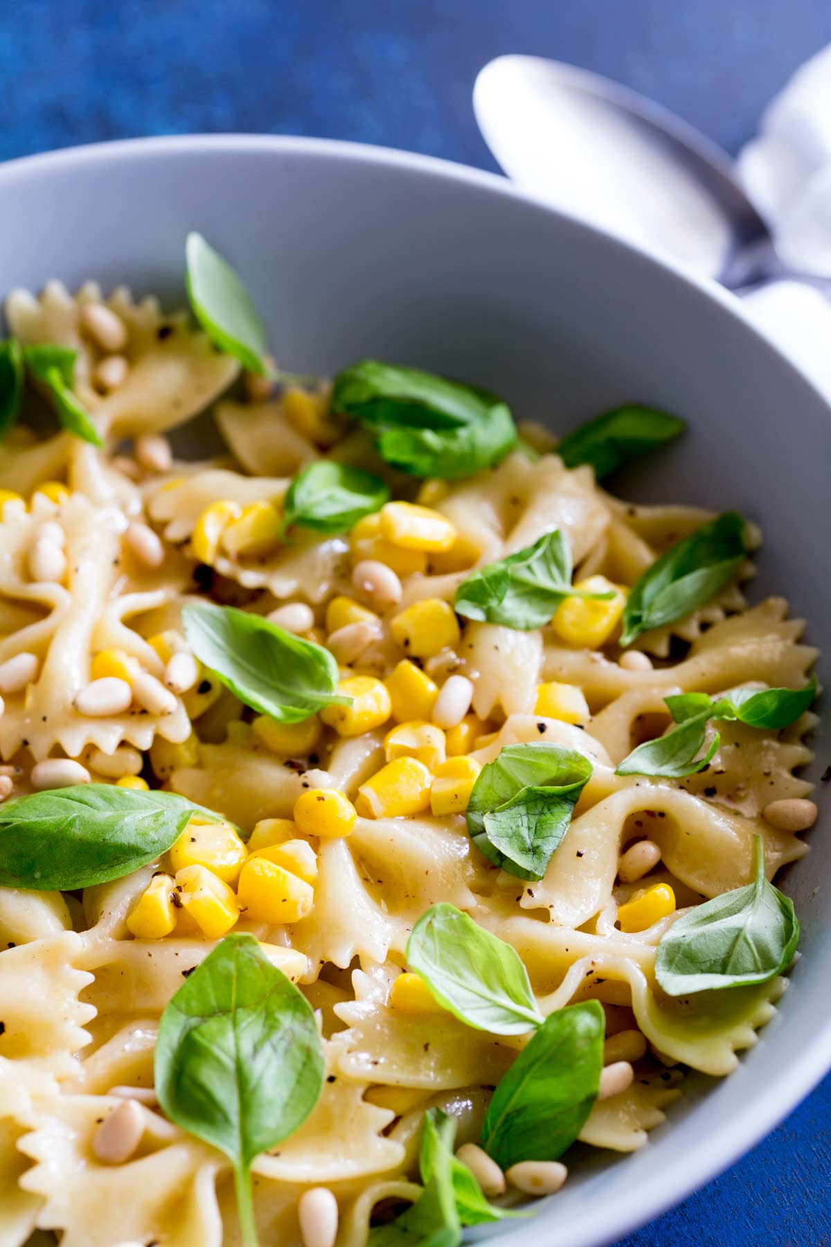 farfalle pasta in a grey bowl with basil and corn