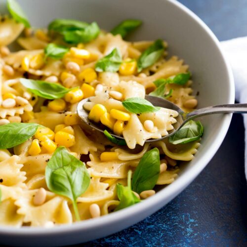 close up on corn, pasta, basil and pine nuts on a spoon
