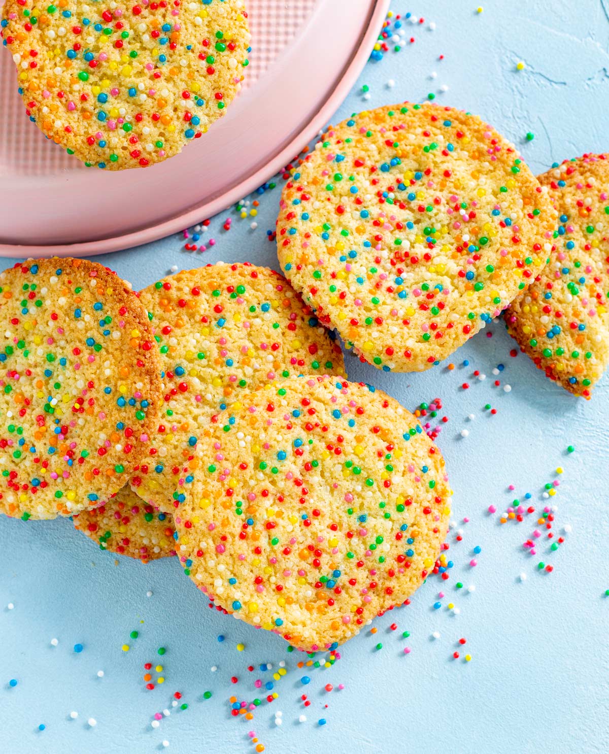 sprinkle cookies on a blue table with sprinkles scattered around