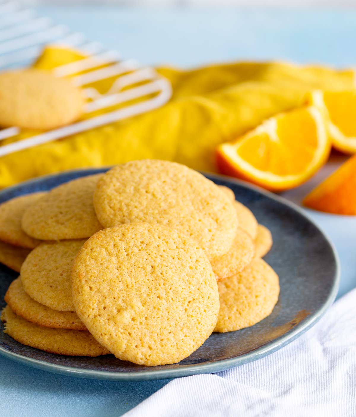 orange cookies stacked on a plate with a yellow napkin