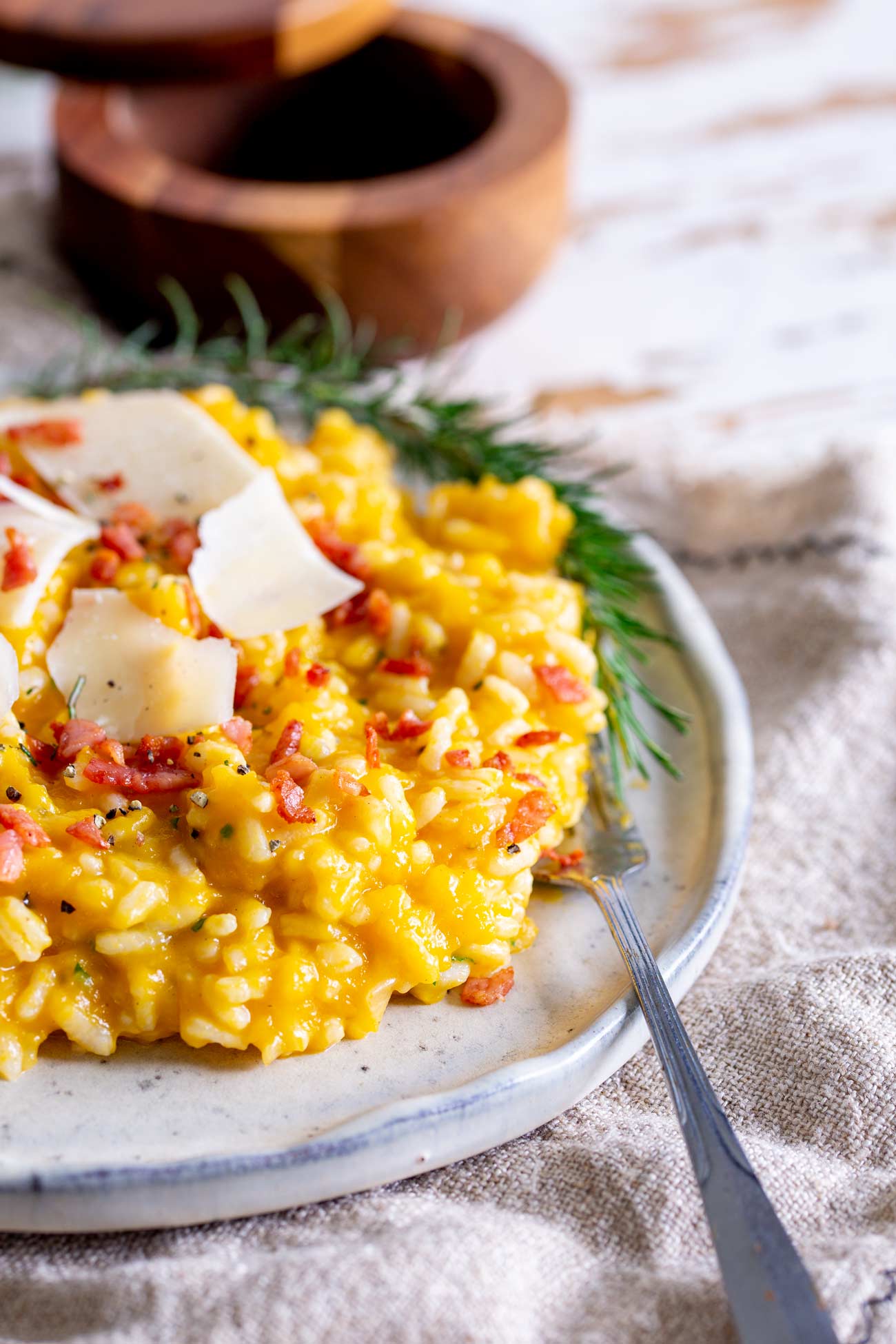 a rustic plate of pumpkin bacon risotto with a sprig of rosemary