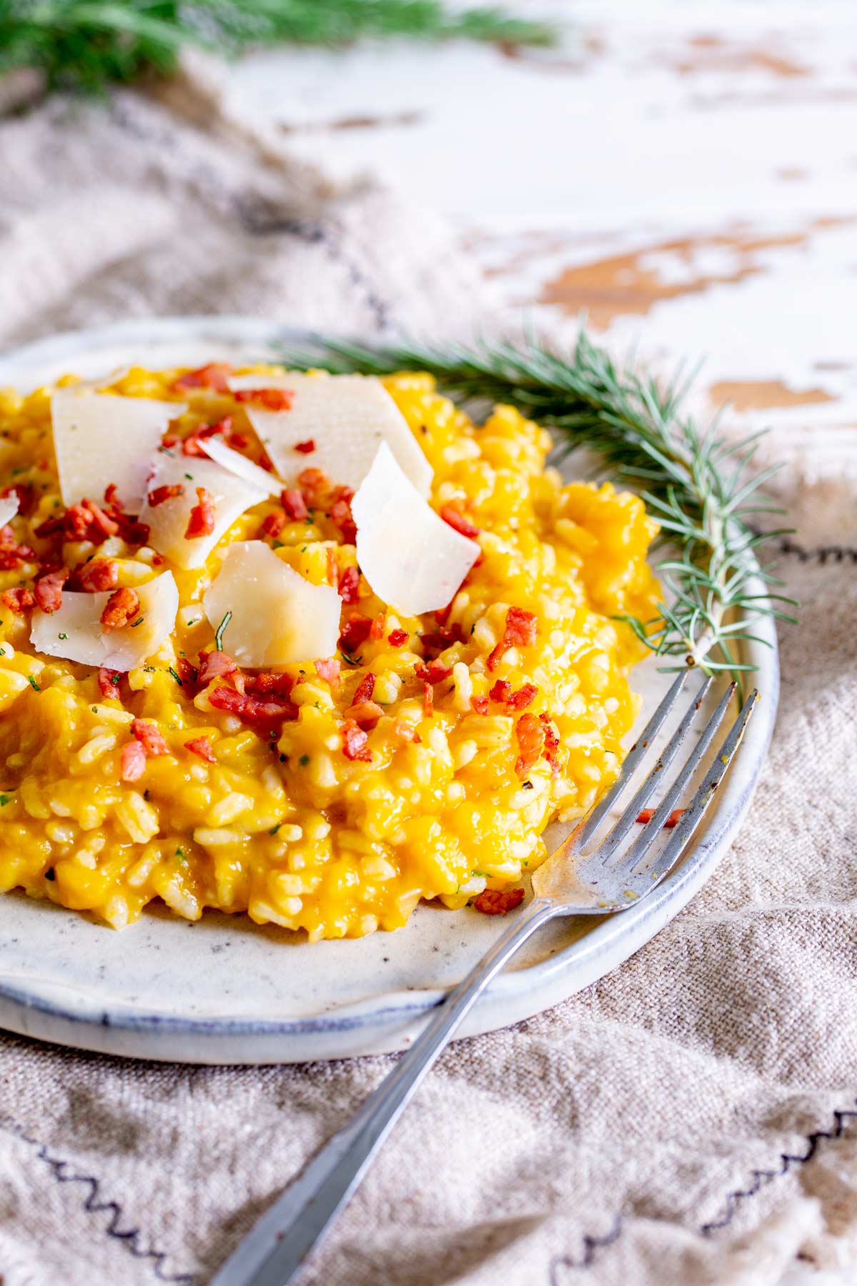 a fork on the side of a rustic plate of yellow risotto