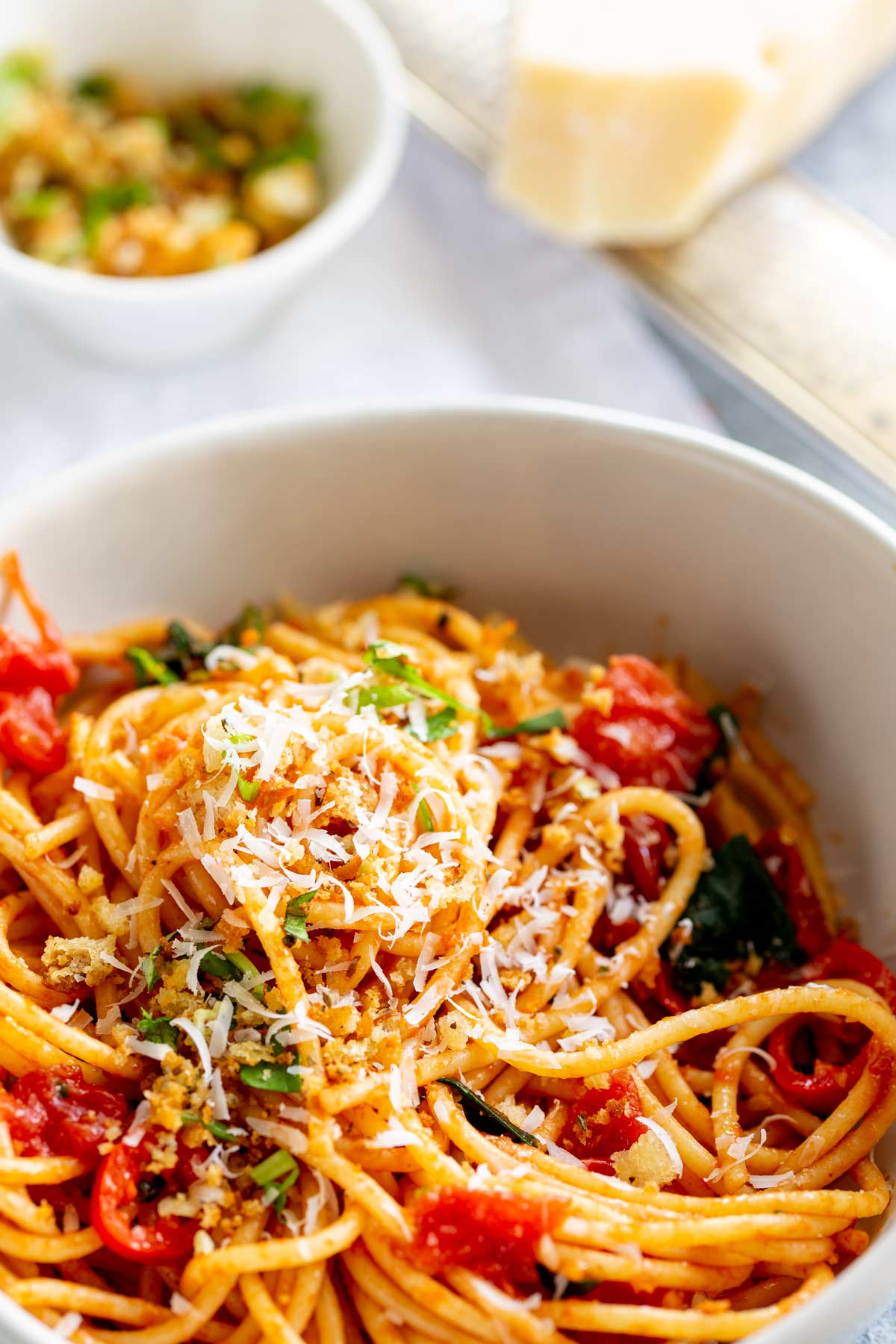a small white bowl of spicy tomato pasta with parmesan on top