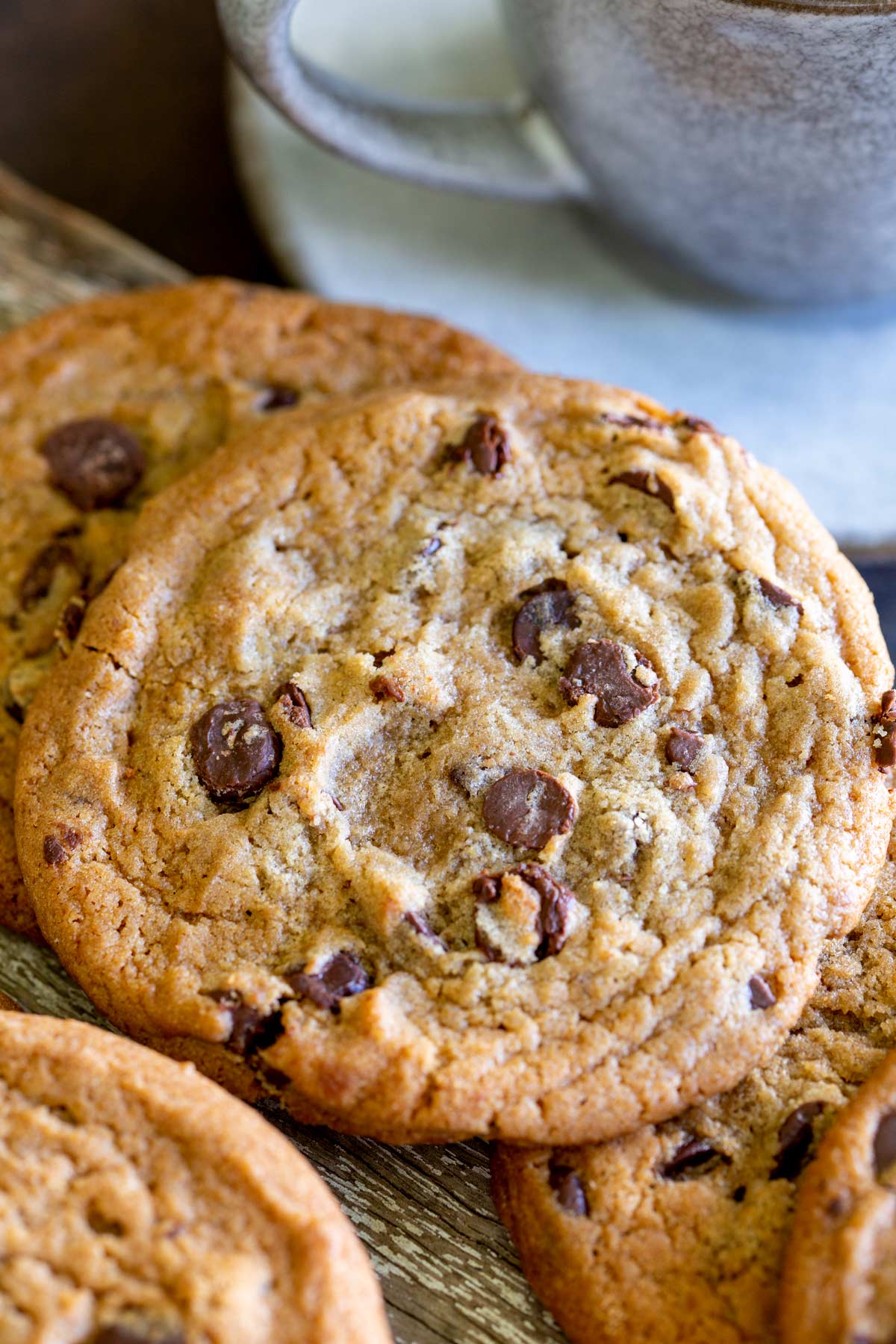 close up of a stack of chocolate chip cookies with cup of tea