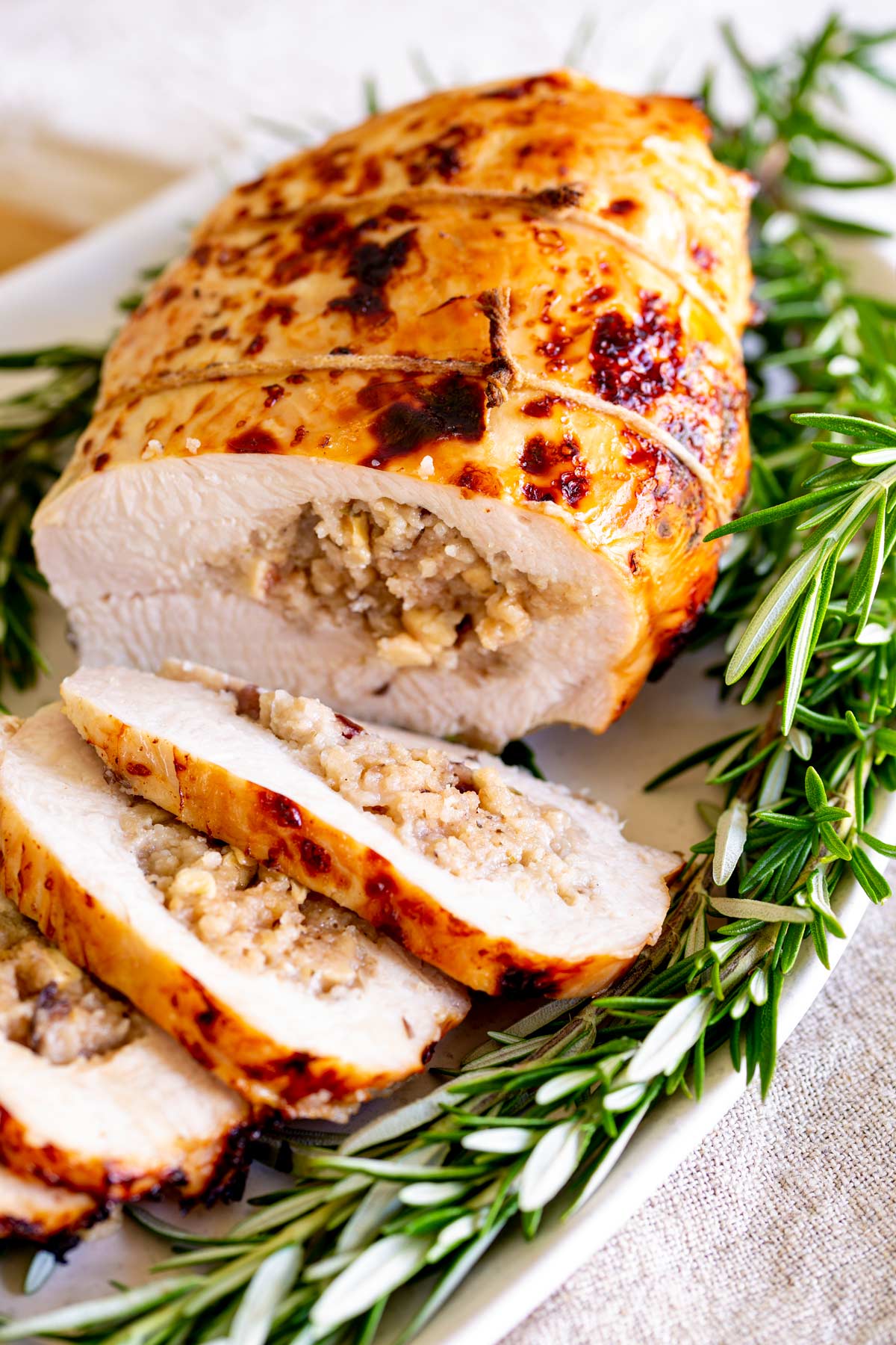 rolled turkey breast on a plate with rosemary