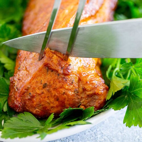 close up on a knife cutting a pork tenderloin