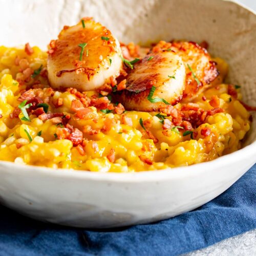 close up on the scollops on top of a pile of pumpkin risotto with bacon