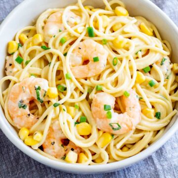 Close up on some shrimp on top of a bowl of corn pasta