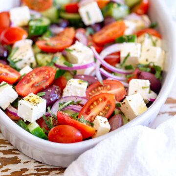 close up on sliced tomatoes and cubed feta in a bowl of salad