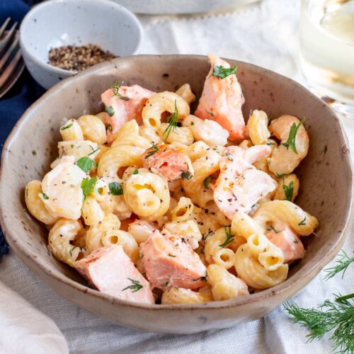 a rustic brown bowl with spiral pasta with cream and seafood in it