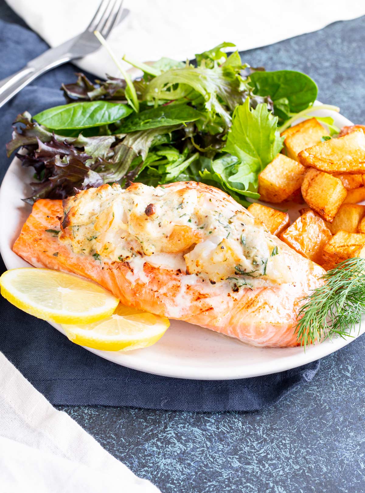 a stuffed salmon fillet on a plate with cubed potatoes and salad
