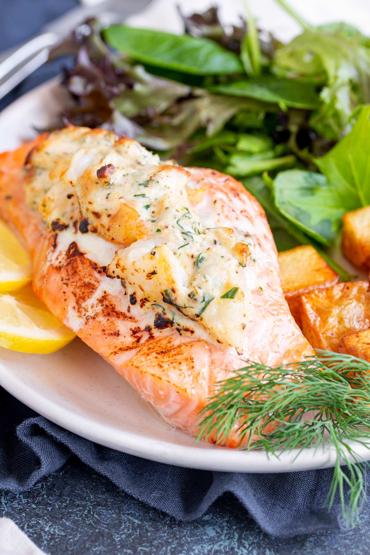 a salmon fillet stuffed with creamy shrimp on a white plate with salad