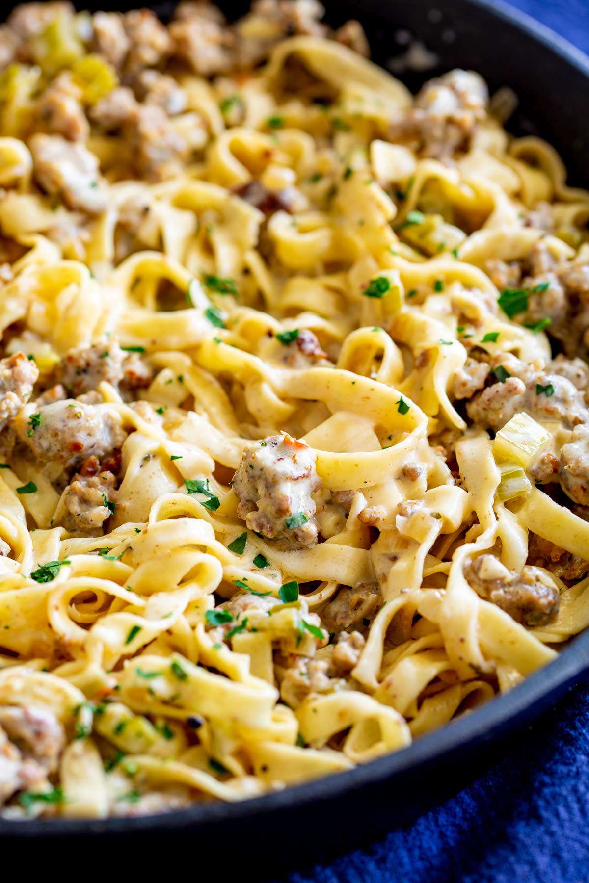 a skillet of cream pasta with sausage and herbs