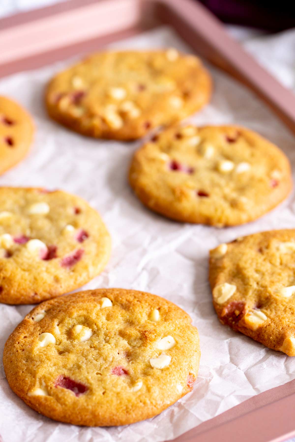 6 baked cookies on a pink sheet pan lined with parchment paper