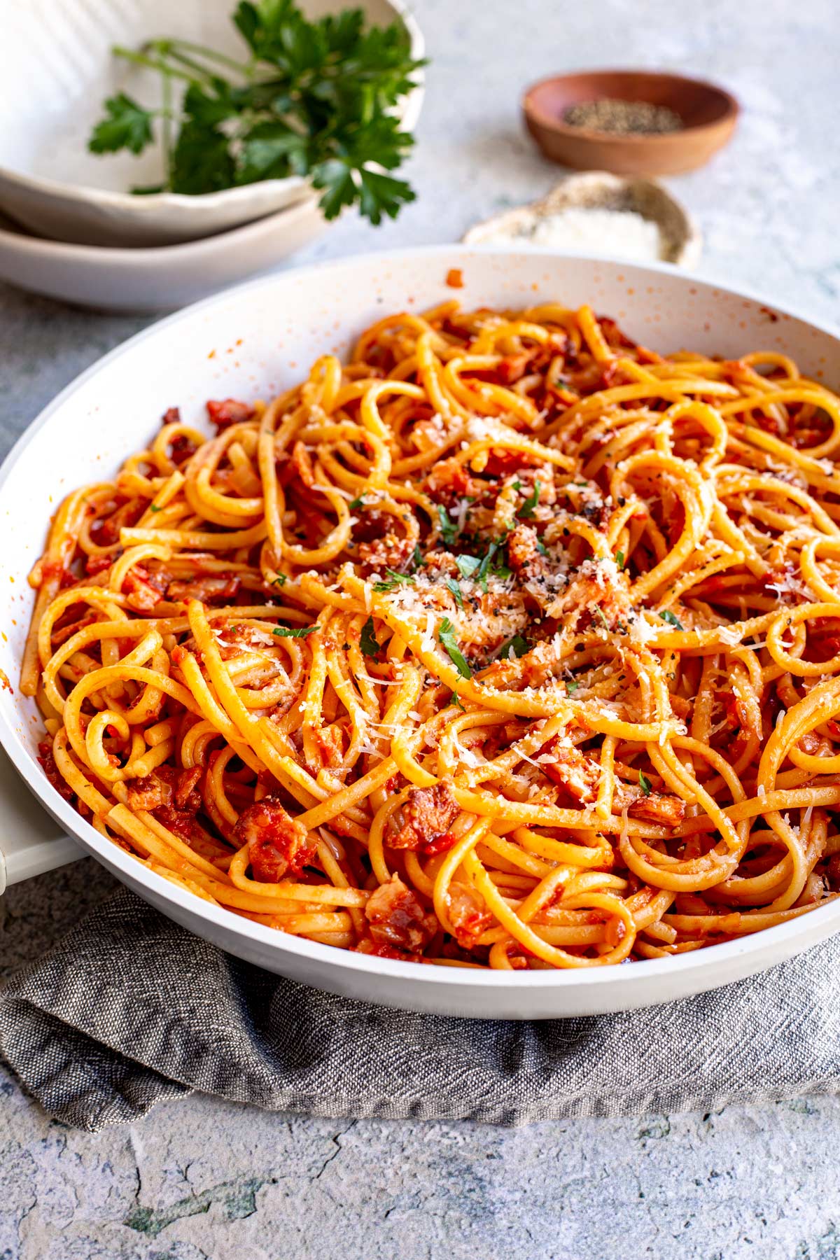 linguine in a skillet with a rich tomato bacon sauce mix through it