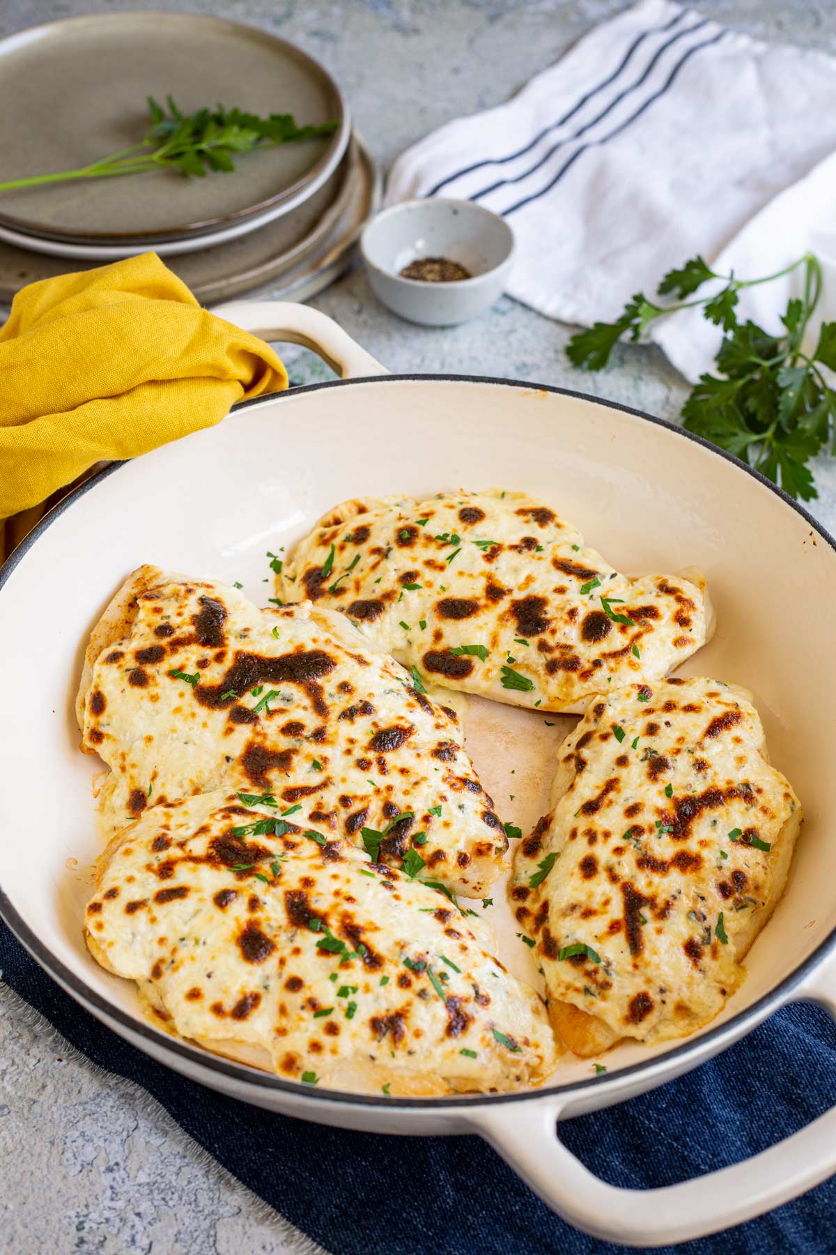 4 chicken breasts covered in melted cheese in a pan on a table with a yellow napkin