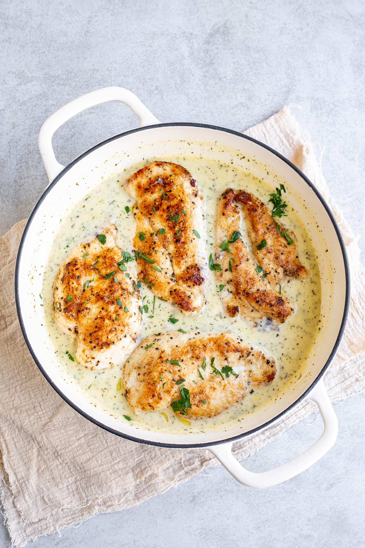 4 chicken breast fillets in a creamy sauce in a cast iron skillet
