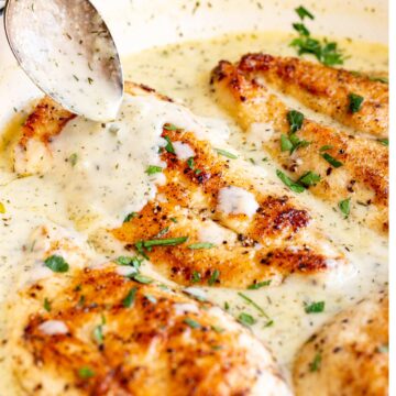 a spoon drizzling creamy sauce over a chicken breast