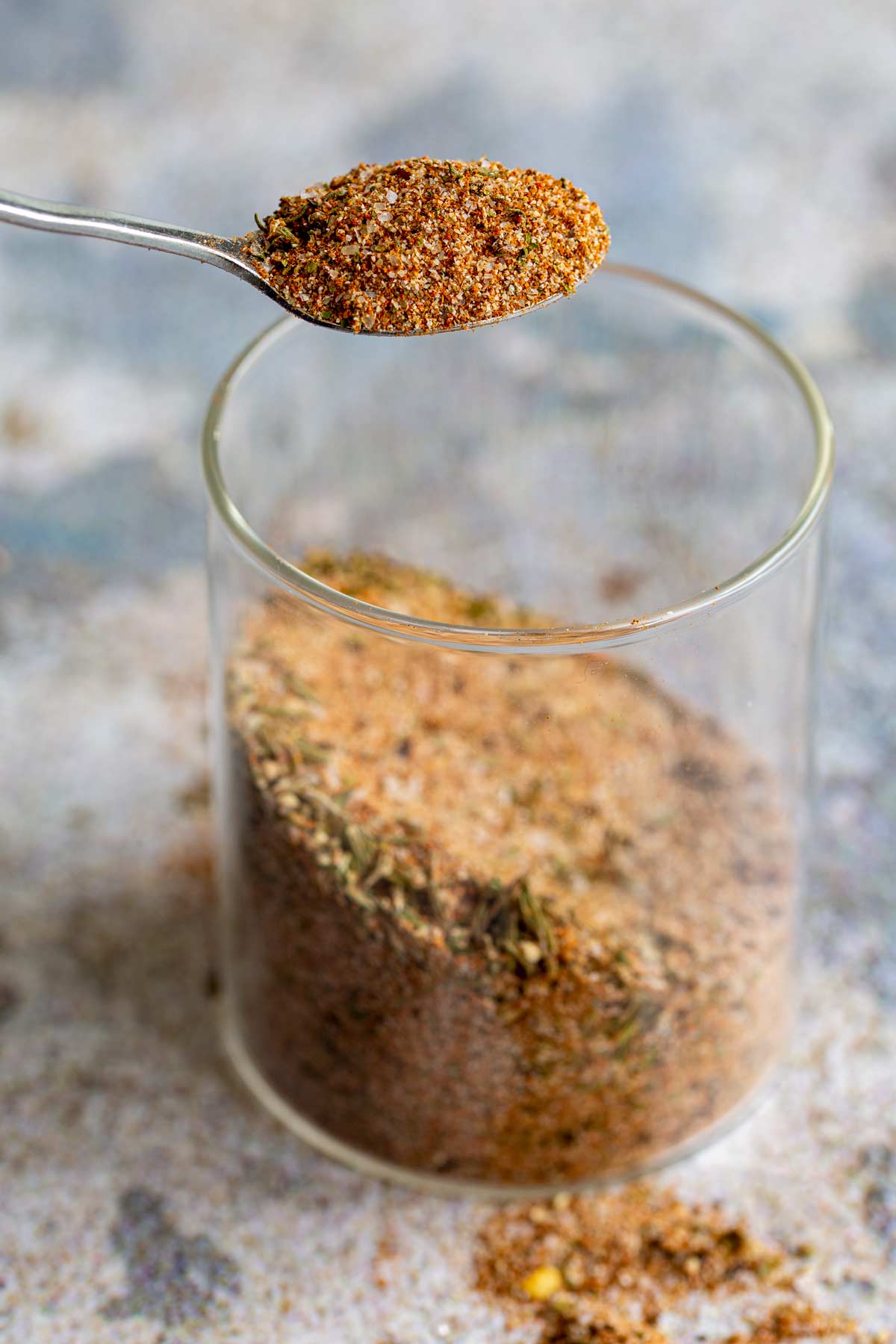 a spoon lifting a seasoning blend from a glass jar