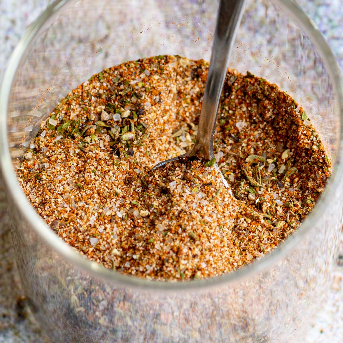 close up on a spoon dipping into a jar of Jamaican jerk seasoning
