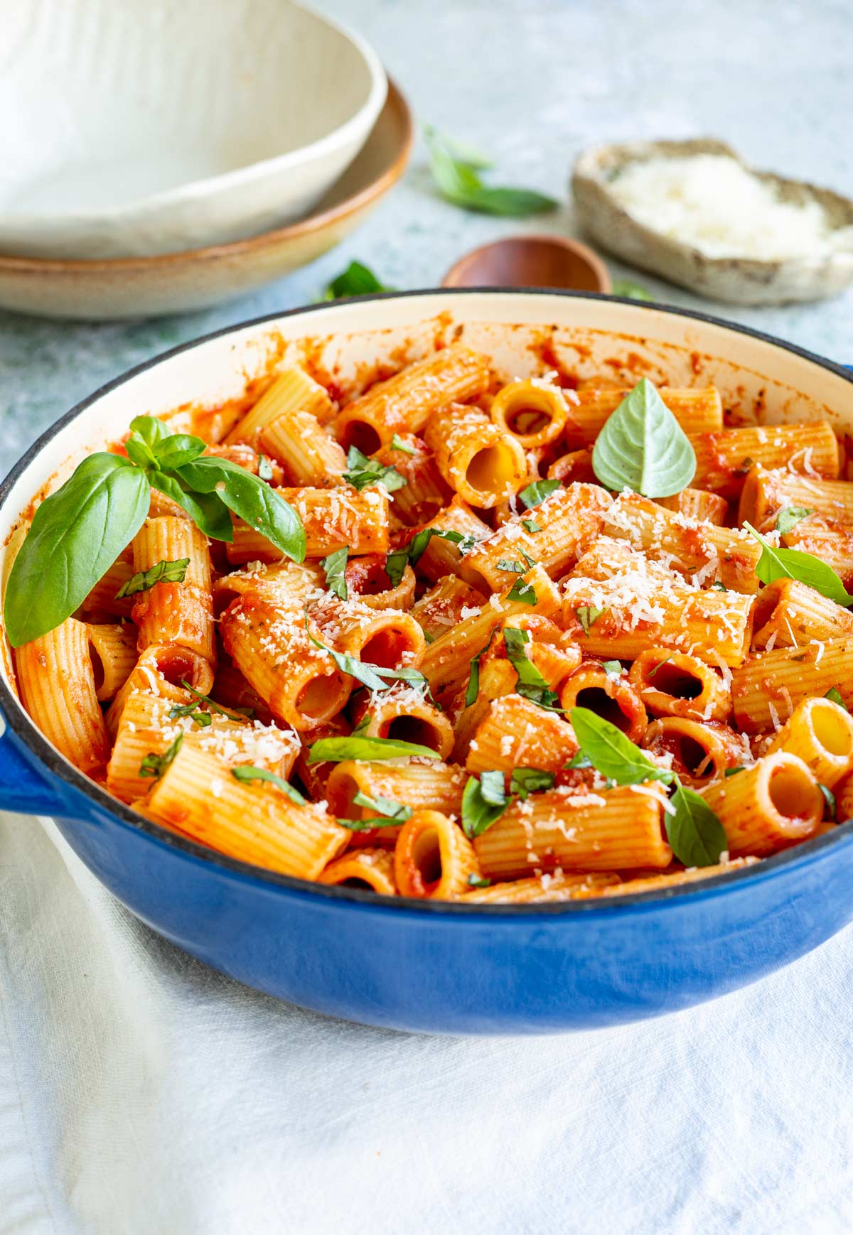 a blue cast iron skillet filled with rigatoni pasta in a tomato sauce