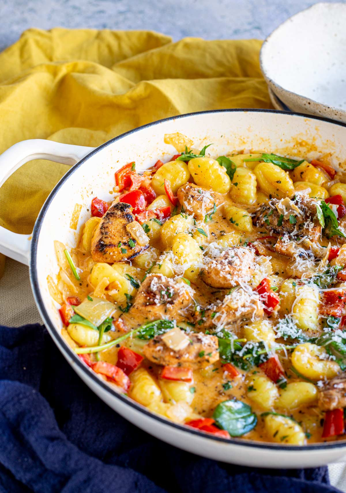 a white cast iron pan filled with gnocchi and chicken