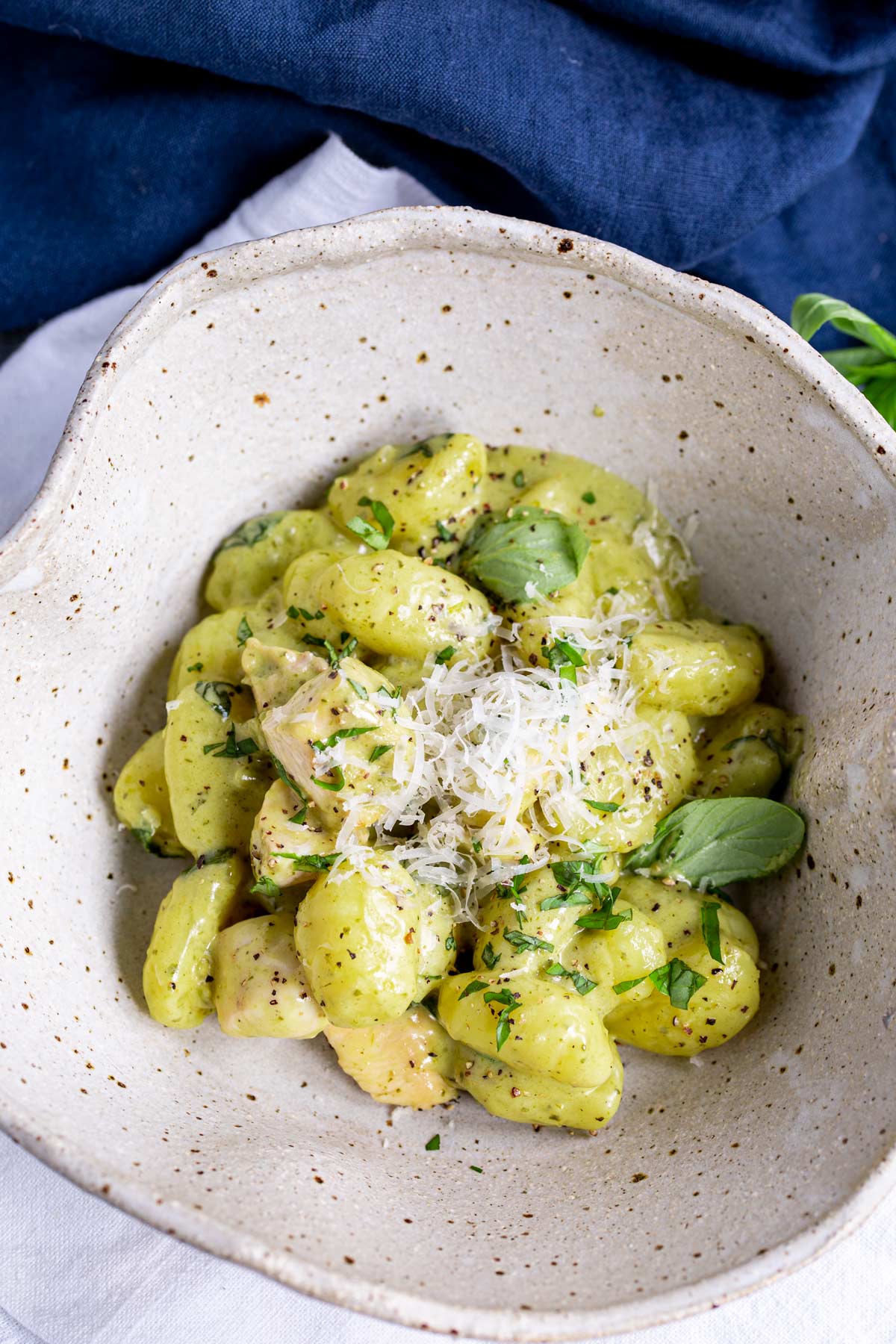 overhead shot of a rustic clay bowl with creamy pesto gnocchi in it