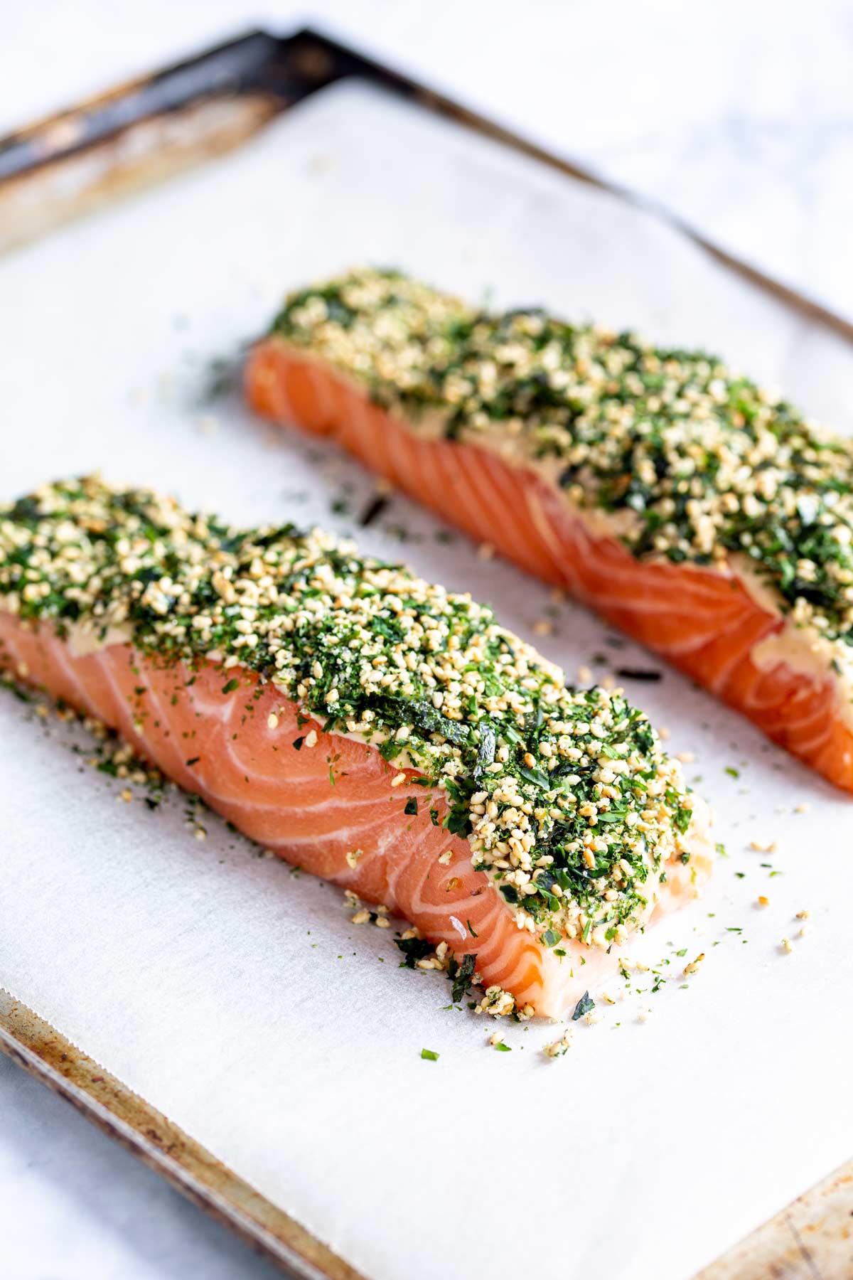two raw salmon fillets on a baking tray coated in Japanese rice seasoning