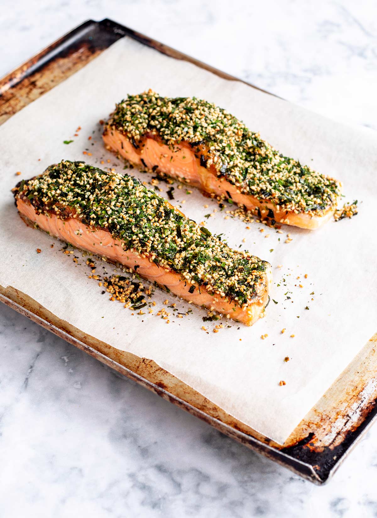 two cooked salmon fillets on a baking tray coated in Furikake