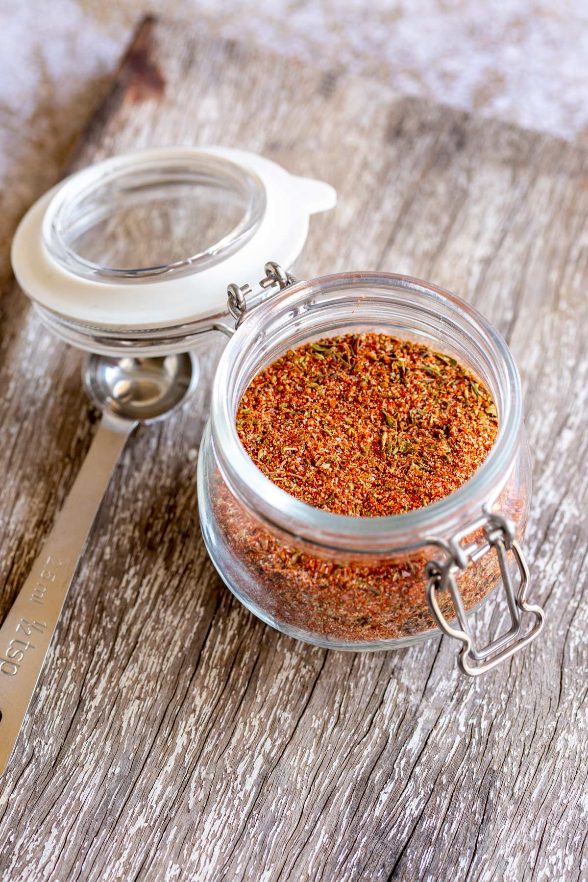 a glass jar with a clip lid. Filled with a blend of seasonings, on a wooden table
