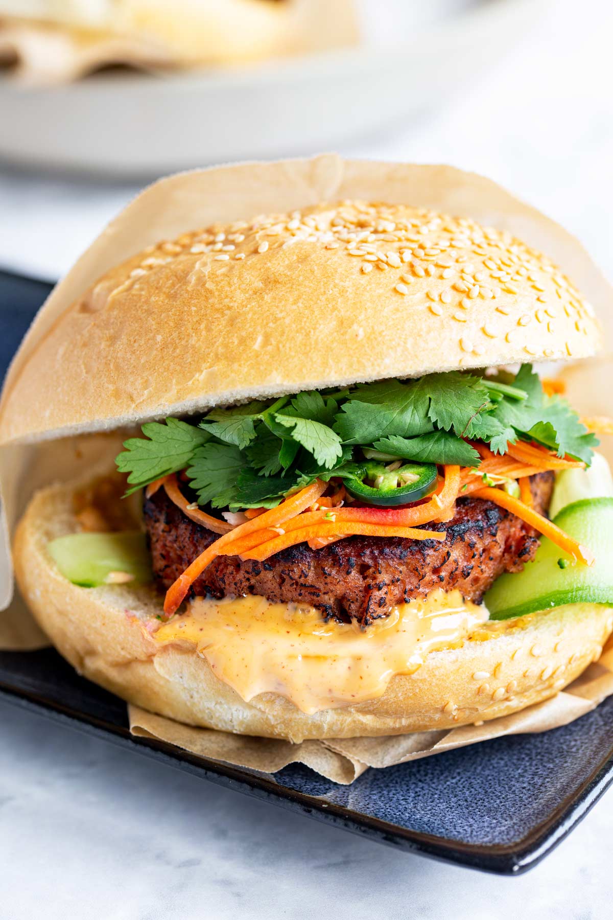 close up of a plant-based banh mi burger on a blue plate