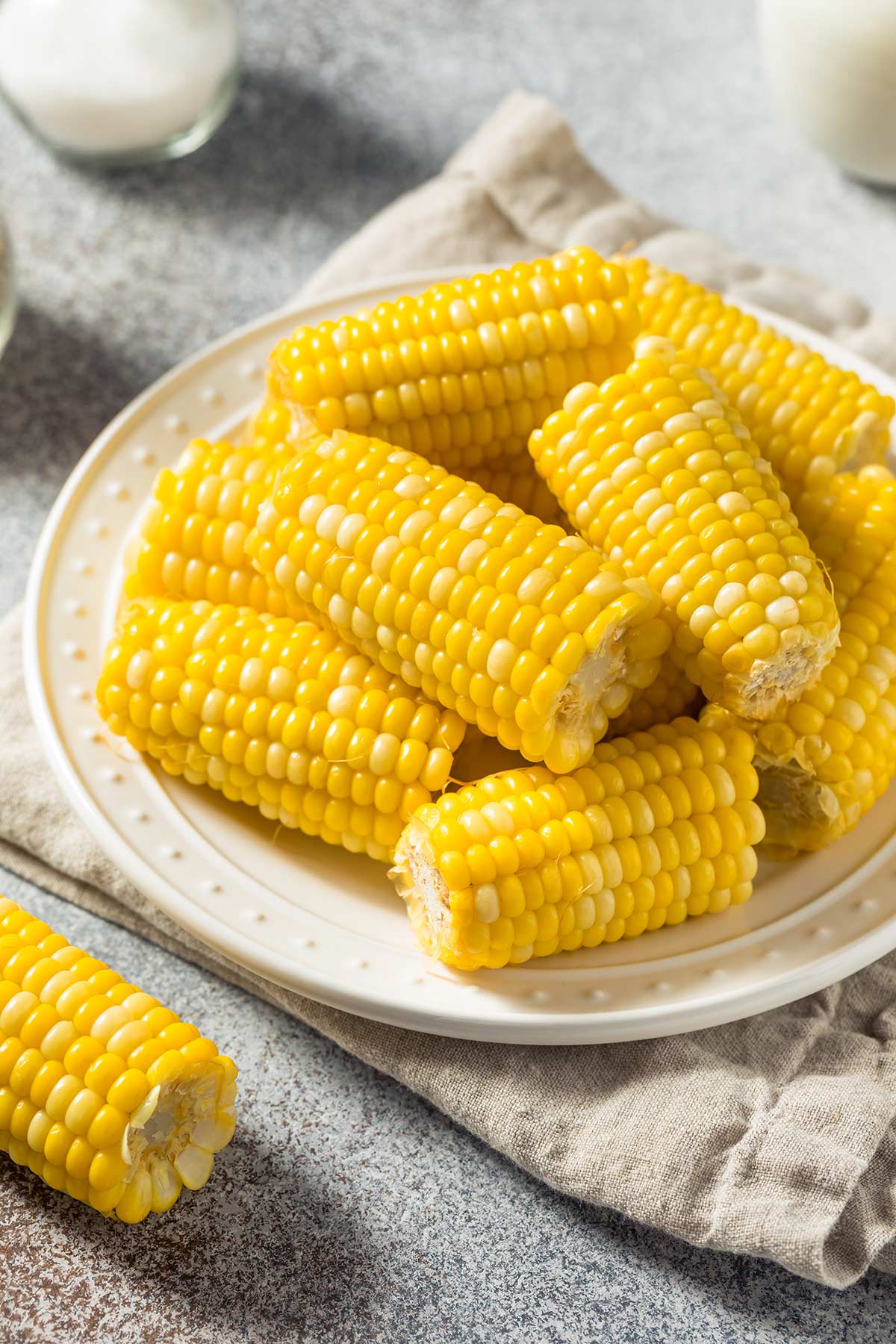 corn halves on a cream plate with a pretty edge on a linen napkin