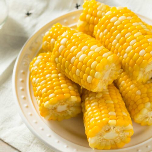 close up on cooked corn on the cob halves in a cream plate