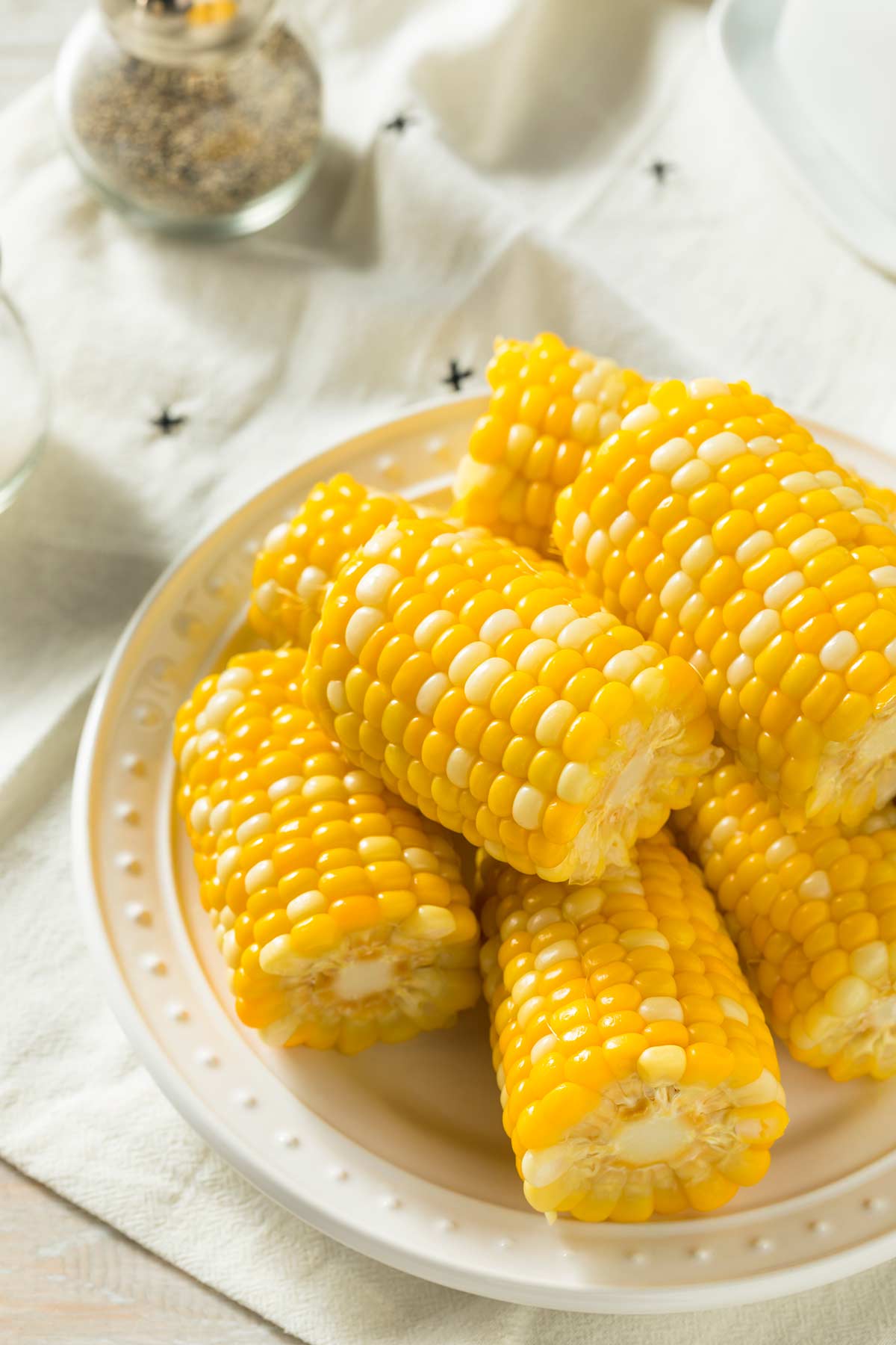 corn on the cob cut in half on a cream plate with a dimpled edge.