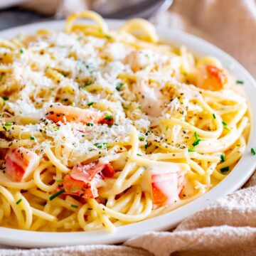 a large pile of creamy spaghetti on a hoot plate with chunks of lobster meat in it