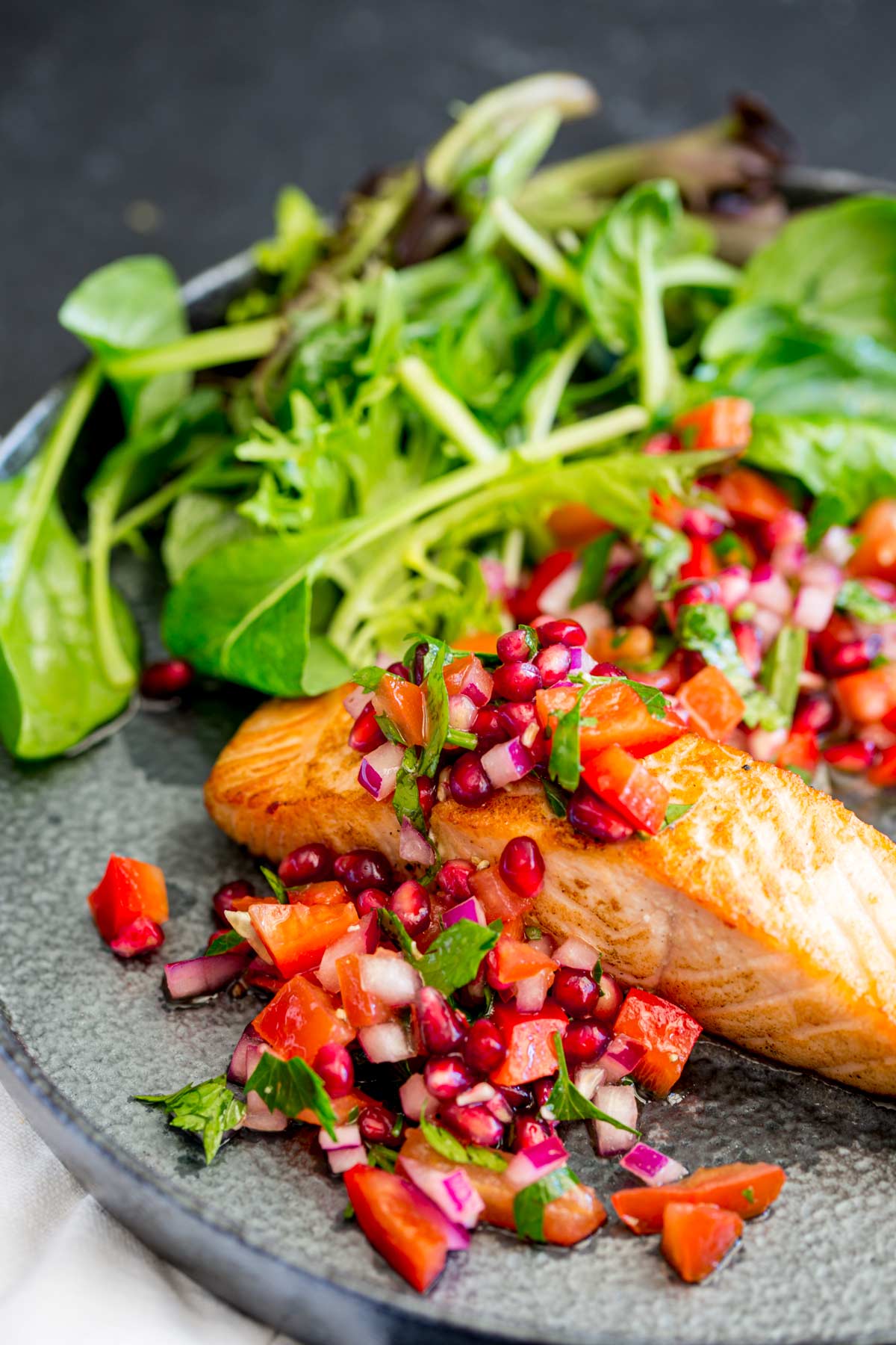 overhead of a seared fillet of salmon with pomegranate arils and tomato over the top