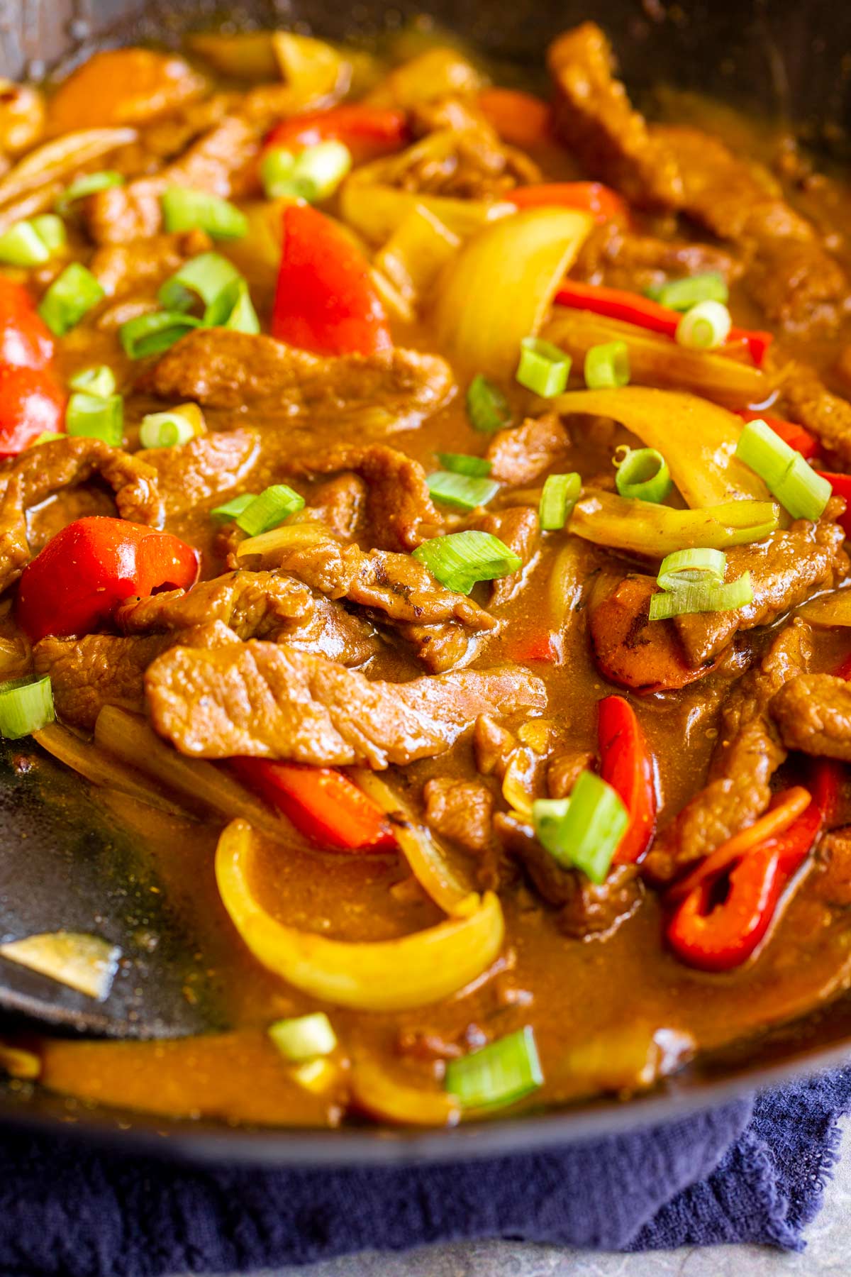 strips of beef with bell peppers and onion with a brown sauce in a wok