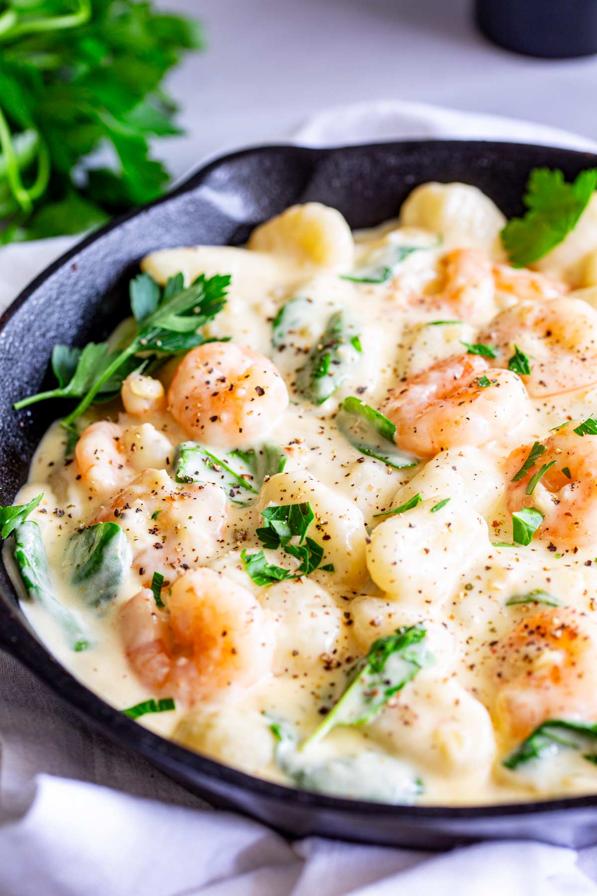 a cast iron skillet filled with gnocchi and shrimp in a creamy white sauce