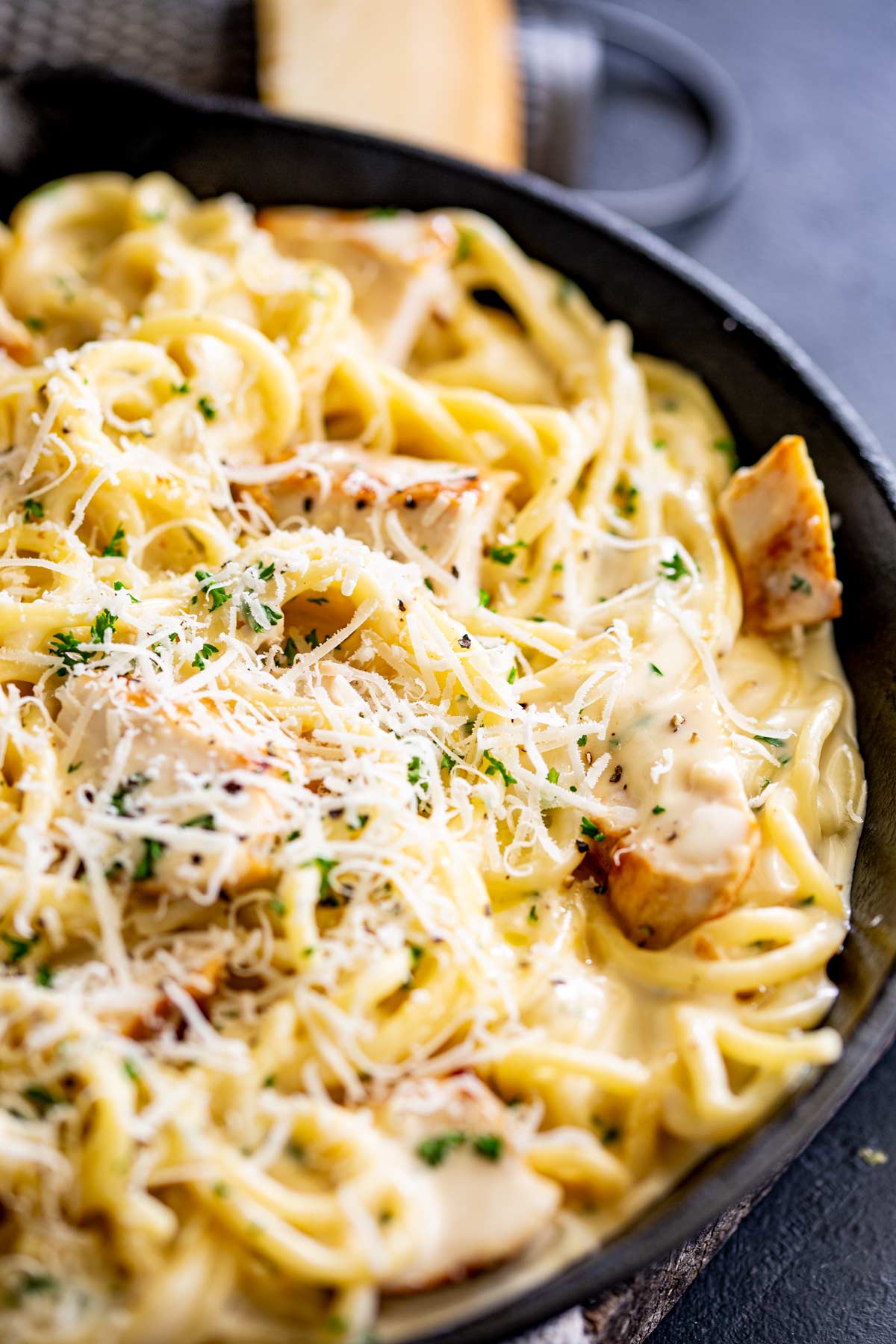 grated parmesan over a pan of creamy garlic chicken pasta