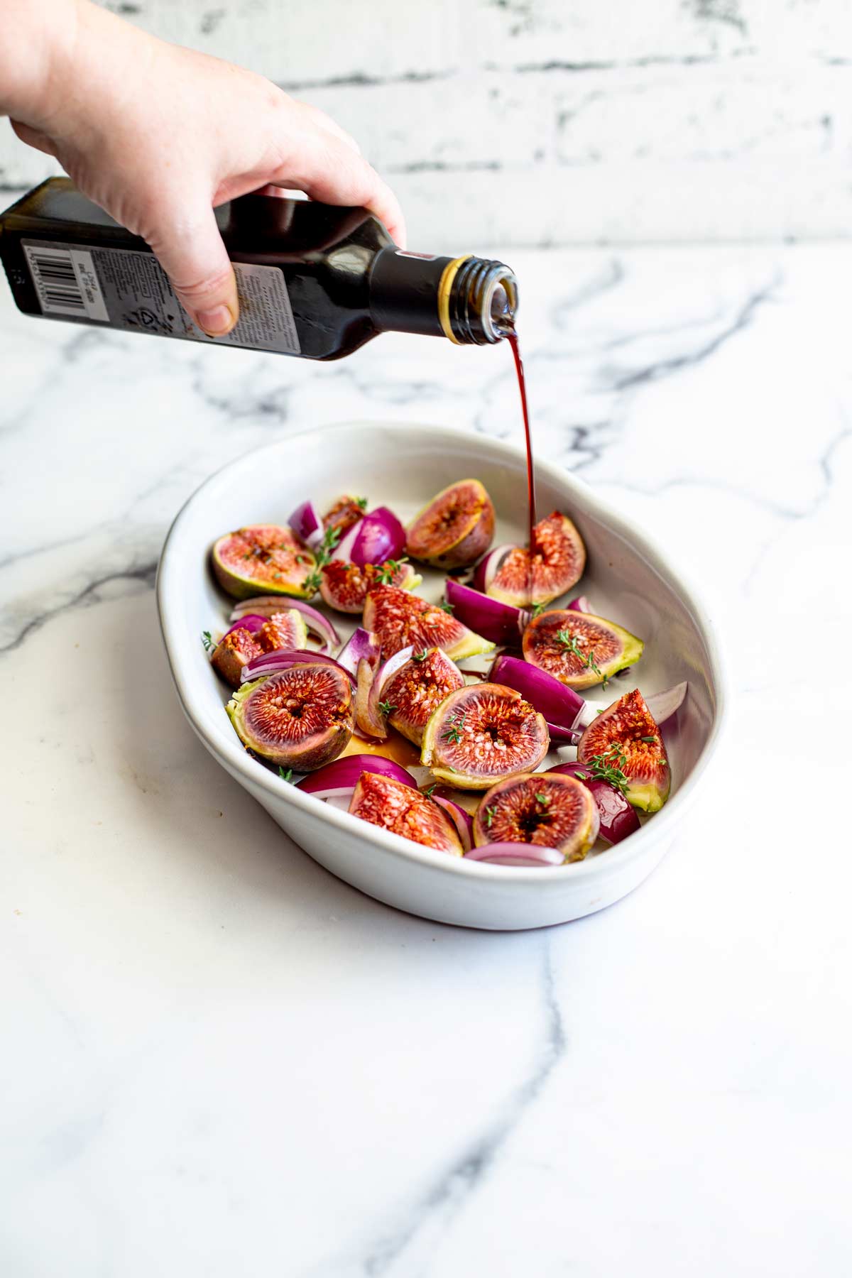 balsamic vinegar being poured into a dish of figs and onions