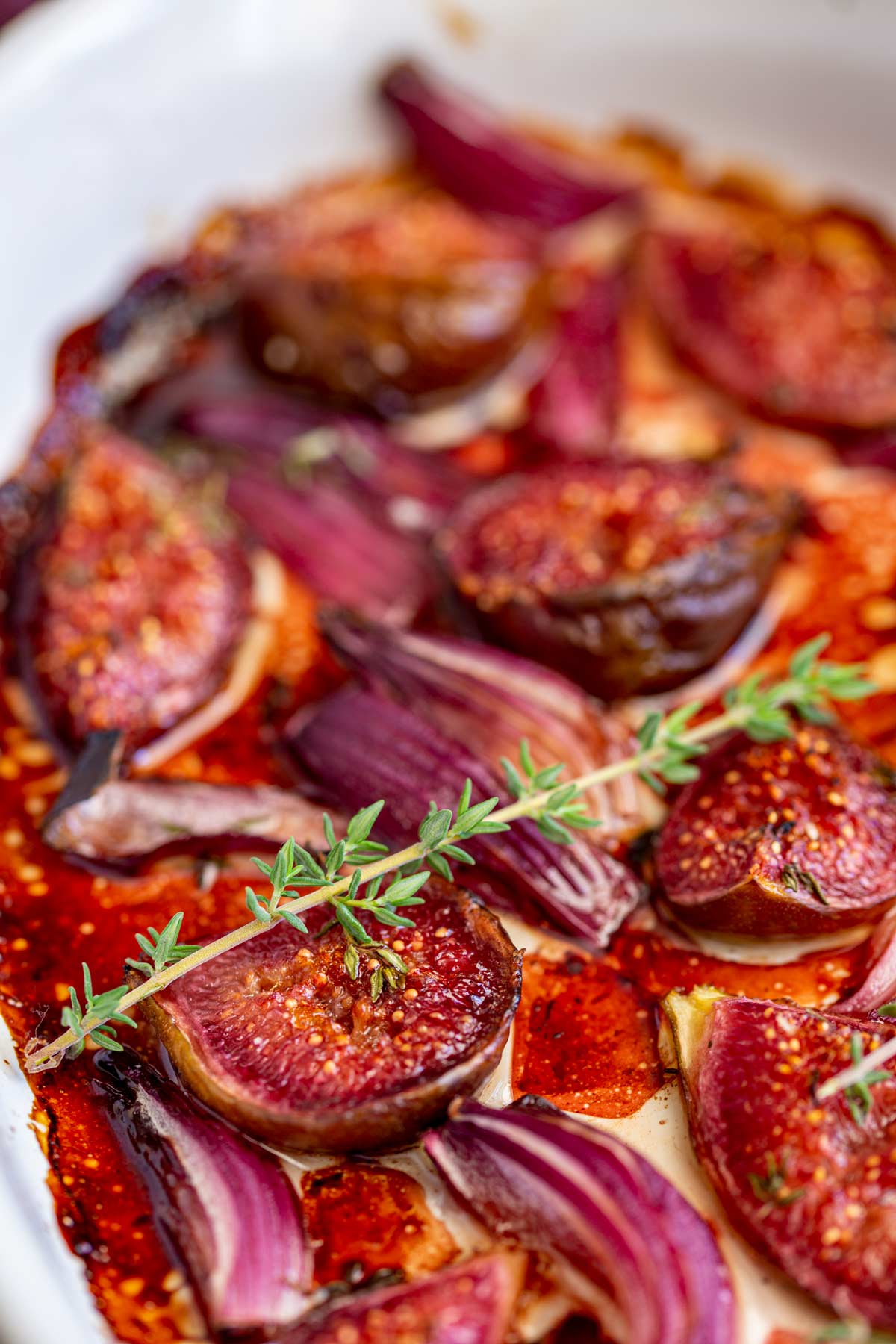 a spring of fresh thyme on top of some roasted figs and red onion