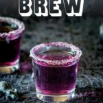 pin image: a purple cocktail in a shot glass, on a halloween inspired table with text overlaid